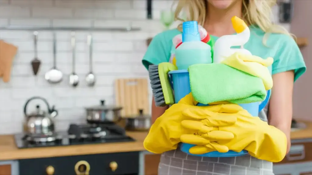 Bucket of cleaning supplies held by a professional ready to clean a kitchen — hire a cleaning service for results like this.