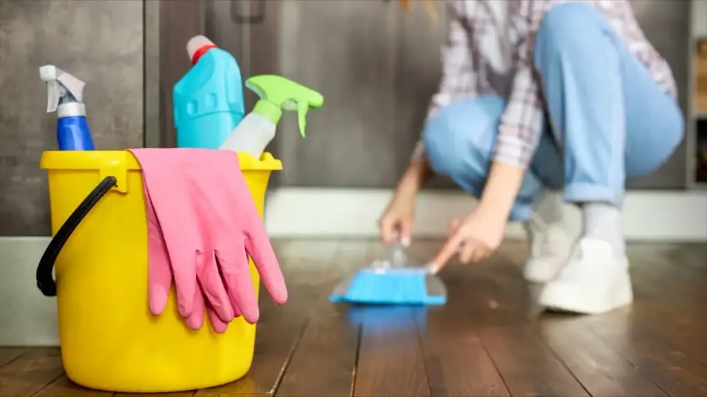 cleaning bucket and woman sweeping wood floor