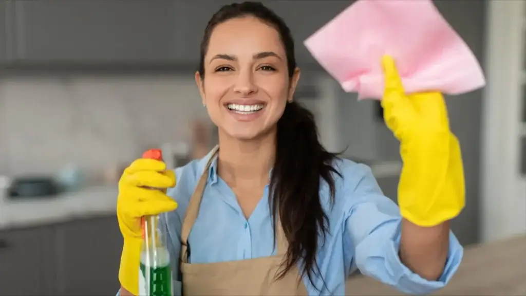 smiling woman with spray bottle and pink cloth