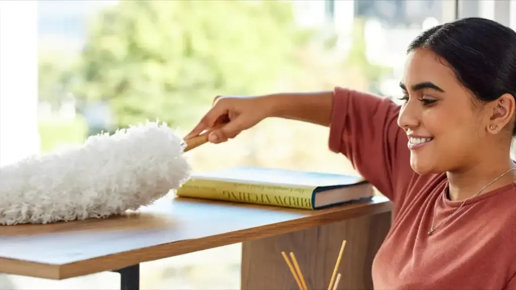 woman dusting bookshelf with feather duster