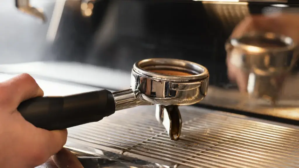 Hand holding portafilter on espresso machine close up