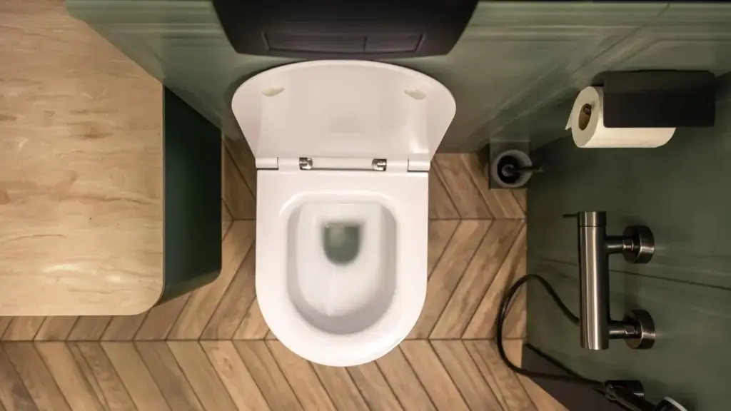 Top view of a clean white toilet in a modern bathroom with wood floor