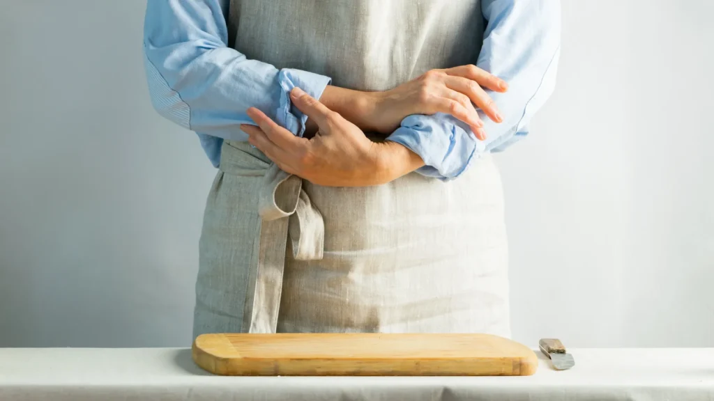 Woman in apron holding a cutting board in the kitchen
