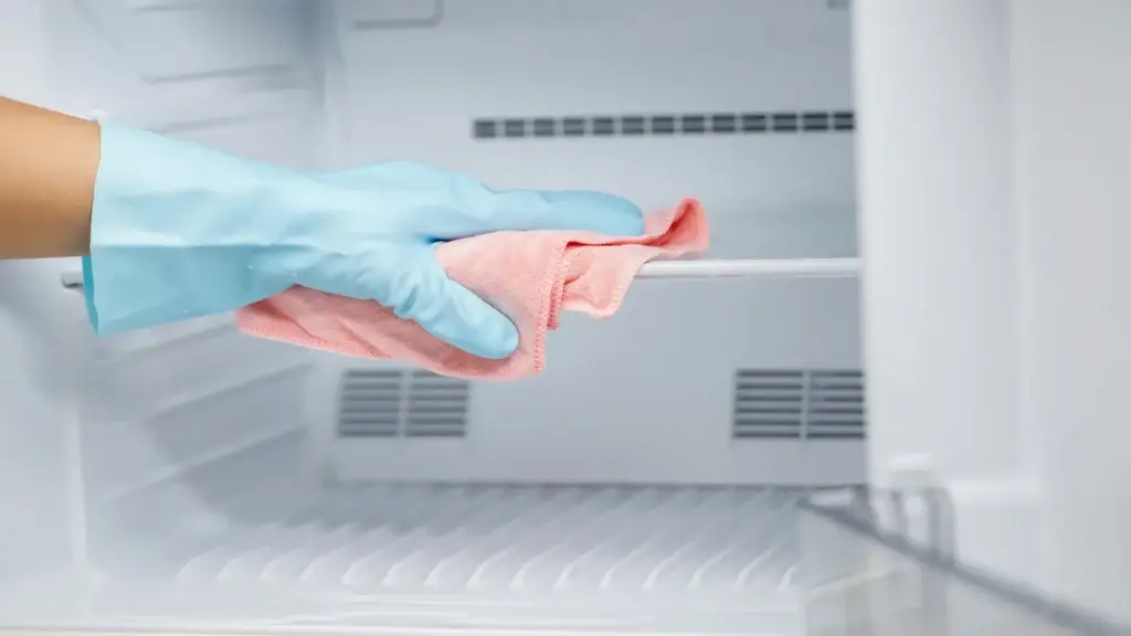 Cleaning staff wiping down refrigerator interior