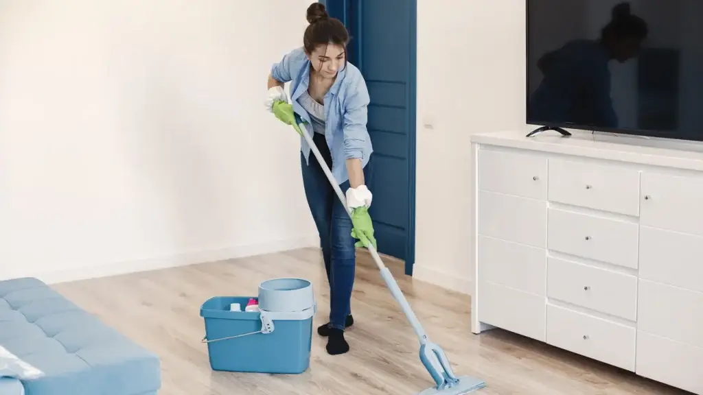 Woman mopping wooden floor in living room