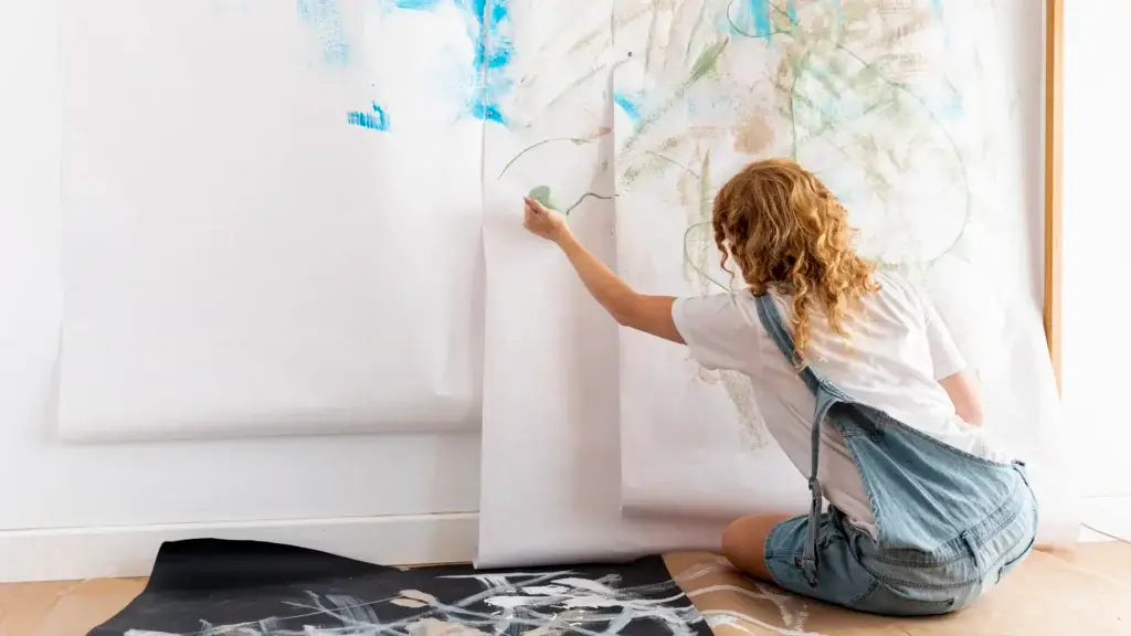 Woman painting abstract mural on paper wall